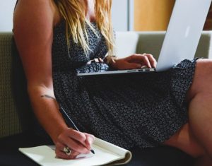 What Is Work Life Integration-An image of a women working and Writing on here couch with a laptop on her lap -image 4 on blog post